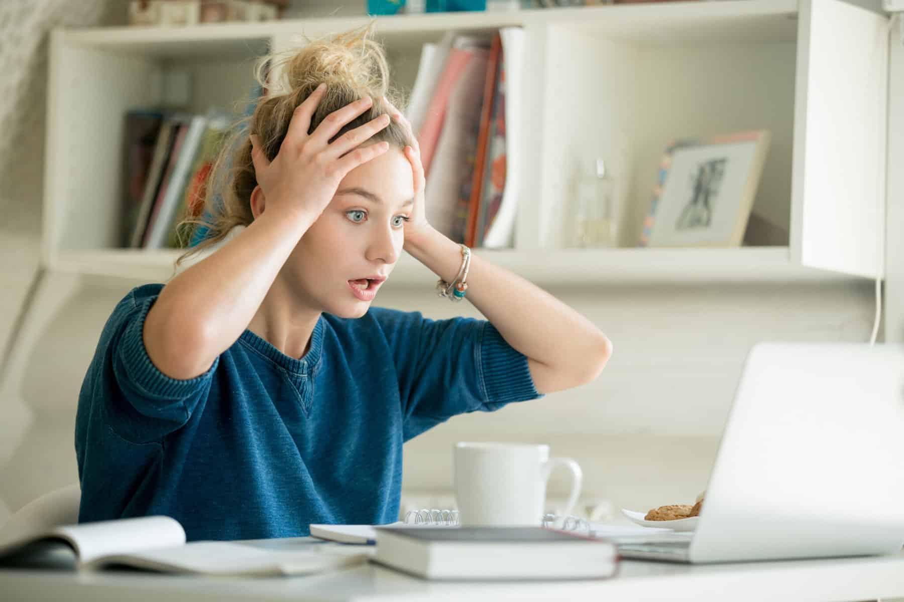 FOMO fear or missing out stress geld persoonlijke financien verlies vrouw met handen in haar voor laptop inflatie